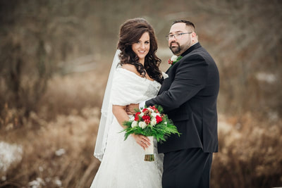 Bride and groom posing in snow with bouquet