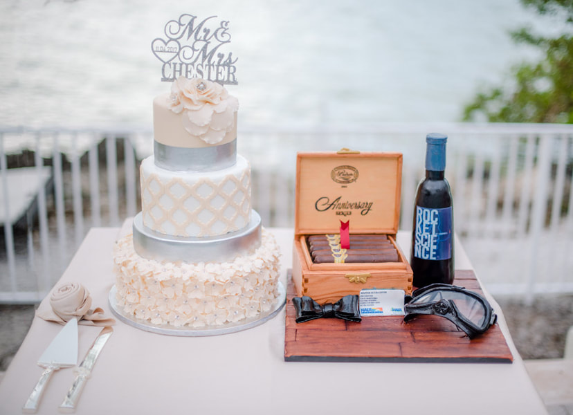 Cigars in a humidor cake, next to a white tiered wedding cake