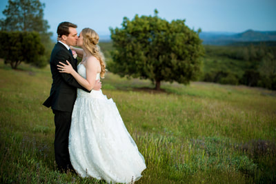 Bride and groom kissing in a field