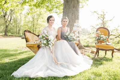 Bride and maid of honor sitting with flowers